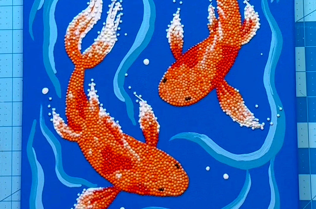 Canvas painted with blue background and two large orange fish swimming 