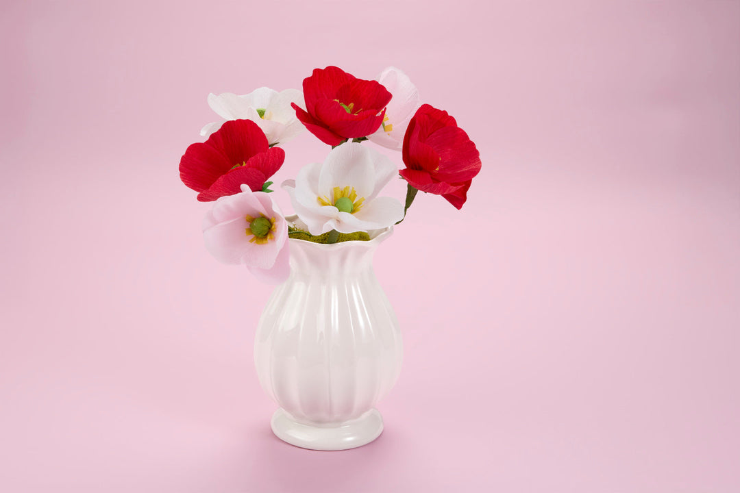 White vase with 6 paper flowers (3 red, 3 white) arranged as a bouquet. 